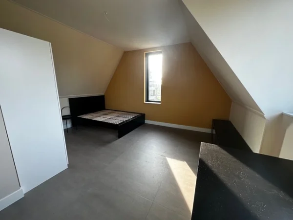 Slaapkamer op zolder met warme wandkleur en houten vloer