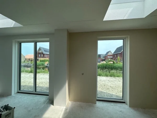Woonkamer met strak afgewerkte wanden en tuindeuren
