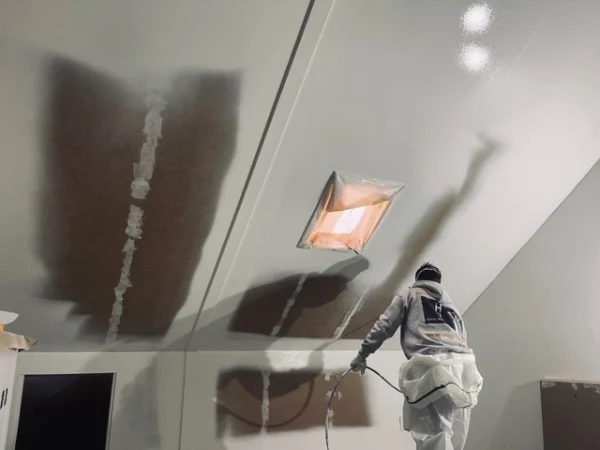 Vakman spuit een zolderplafond strak af